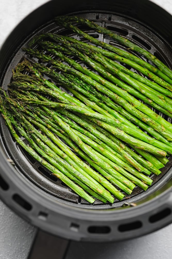 cooked asparagus in an air fryer basket