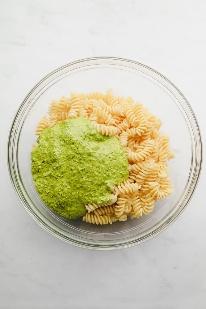 pesto poured on top of cooked pasta in a glass bowl