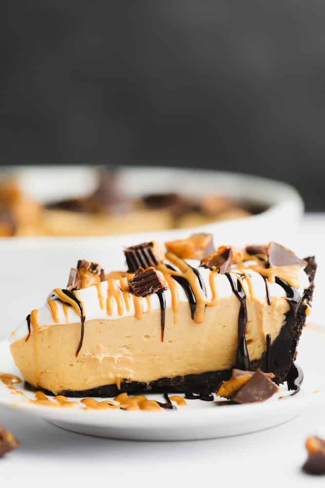 showing a vegan peanut butter pie from the side with whipped cream, peanut butter cups and drizzle of chocolate