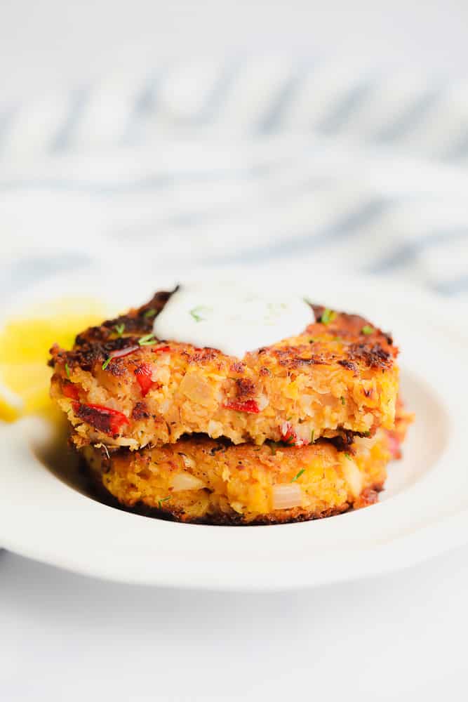 2 crab cakes on top of each other topped with white sauce