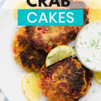pinterest image of a white plate with fried vegan crab cakes next to white dipping sauce and lemon wedges