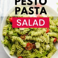 pinterest image of pesto pasta salad with tomatoes in a white bowl