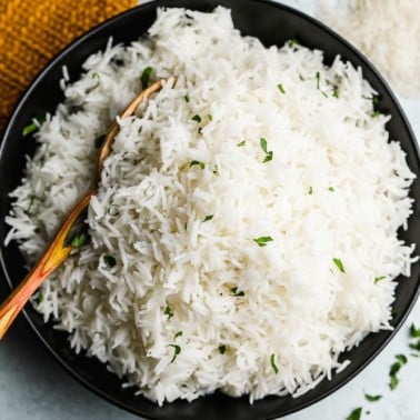 wooden spoon taking a scoop of white rice out of a black bowl