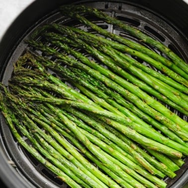 close up of cooked asparagus in an air fryer basket