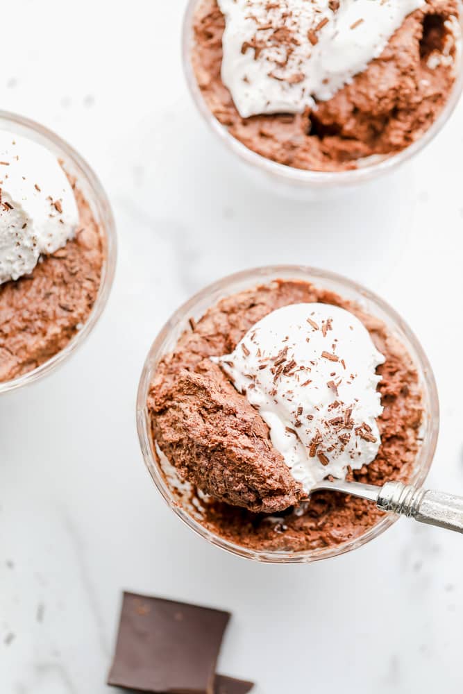 overhead view of a spoon taking a bite of chocolate mousse out of a glass cup