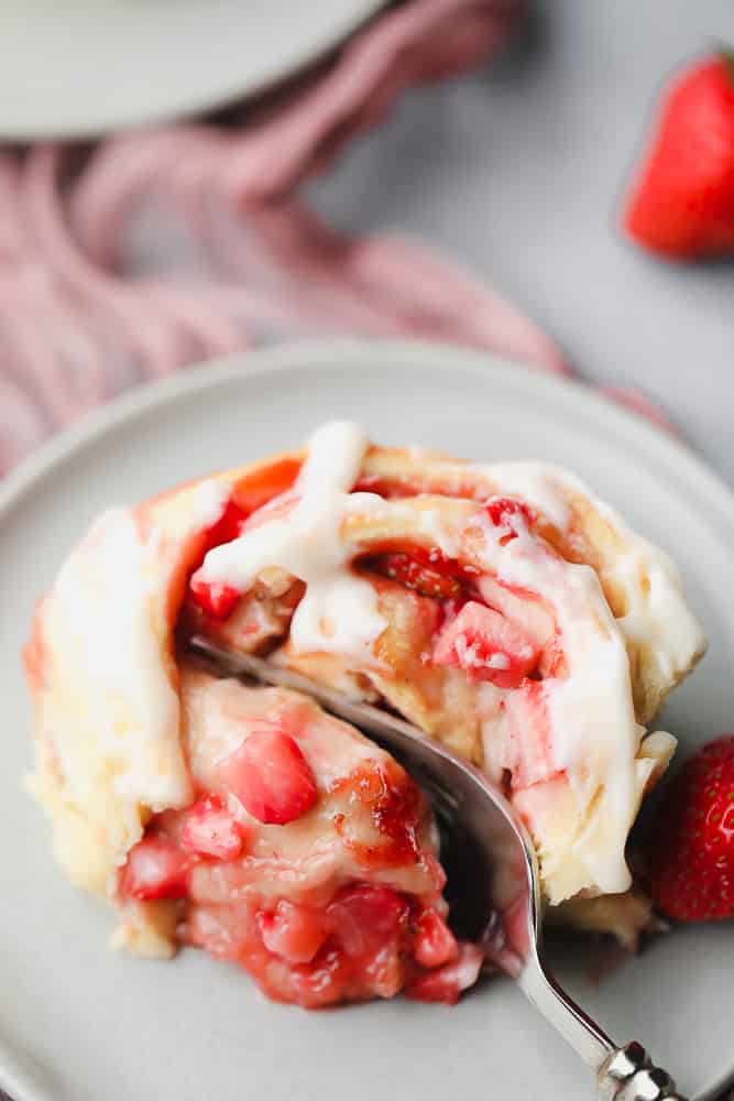 fork cutting into a strawberry roll with icing