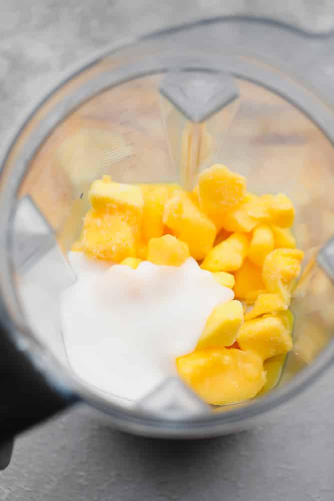 yellow mango chunks and white coconut yogurt in a blender