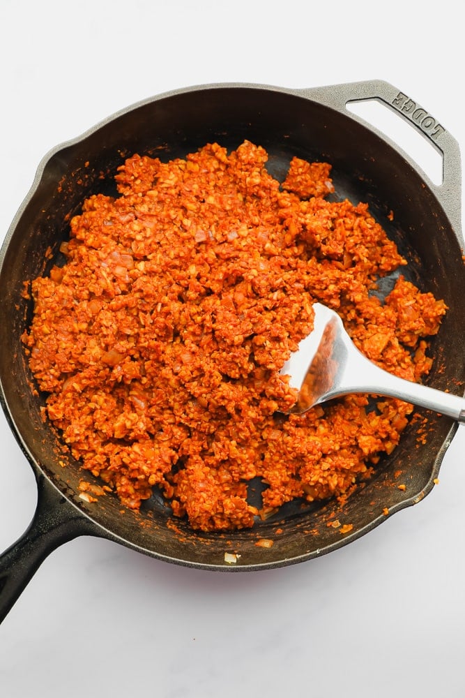 sauteeing orange tempeh in a cast iron skillet