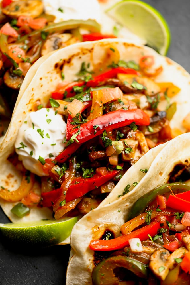 close up on a tortilla stuffed with cooked red bell peppers and onions