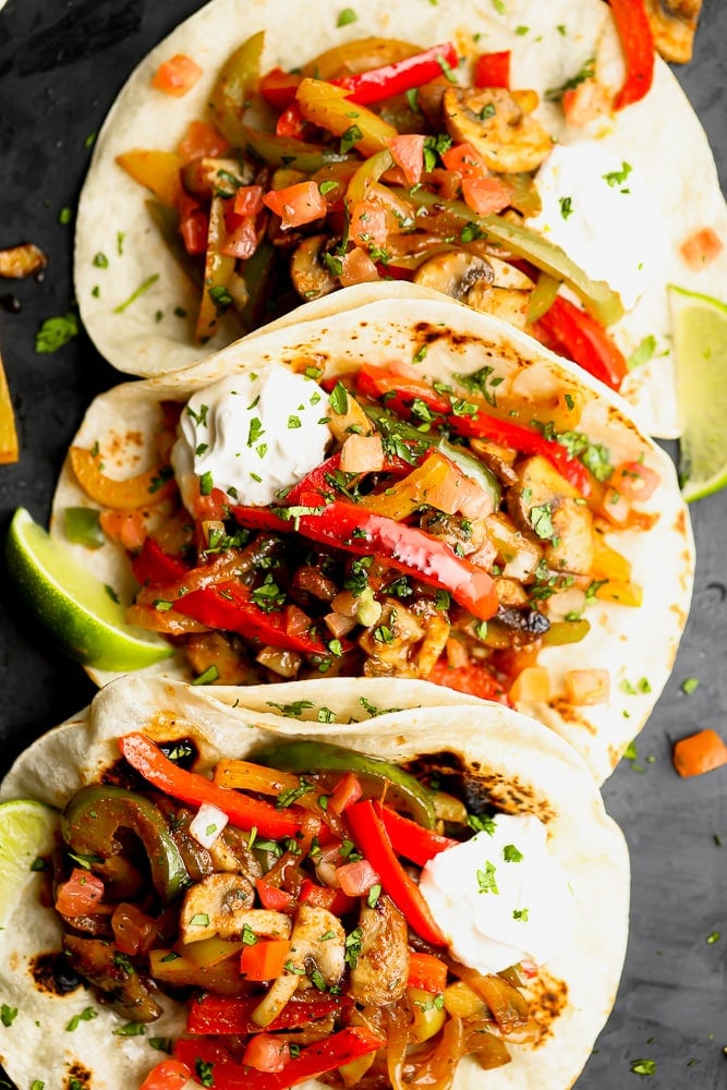 3 tortillas in a row stuffed with sauteed bell peppers, onions, and mushrooms for vegetarian fajitas