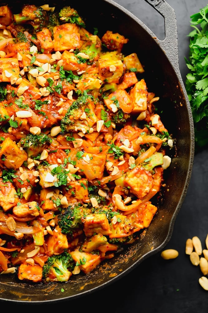 close up of orange stir fry with broccoli in a black skillet