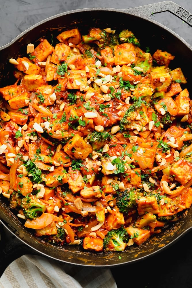 stir fry topped with broccoli and nuts in a cast iron skillet