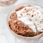 close up on a glass dessert cup holding chocolate mousse topped with whipped cream