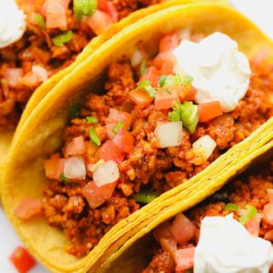 close up on a corn tortilla tempeh taco topped with tomatoes and sour cream