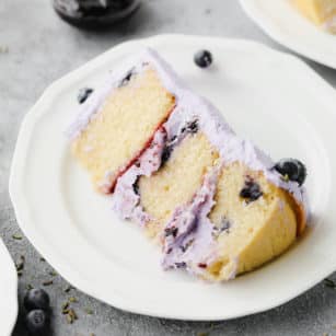 piece of cake on a plate with blueberries and purple frosting