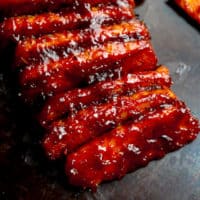 square image of lined up tempeh ribs with bbq sauce