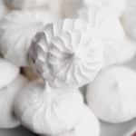 close up on a pile of white vegan meringues cookies on a small grey plate