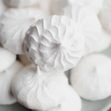 close up on a pile of white vegan meringues cookies on a small grey plate