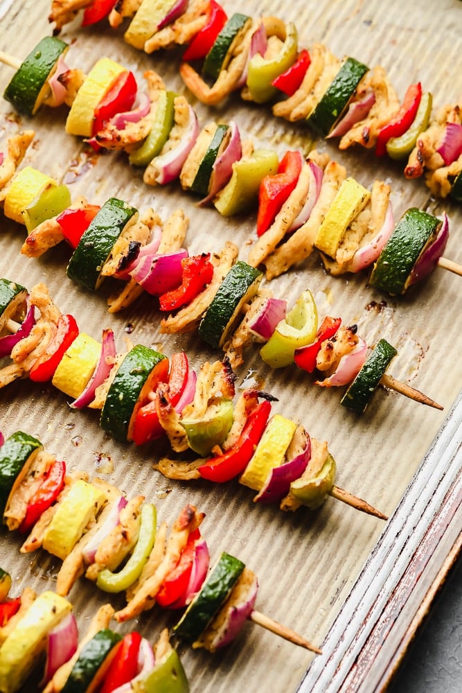 cooked vegetable kebabs on a parchment lined baking sheet