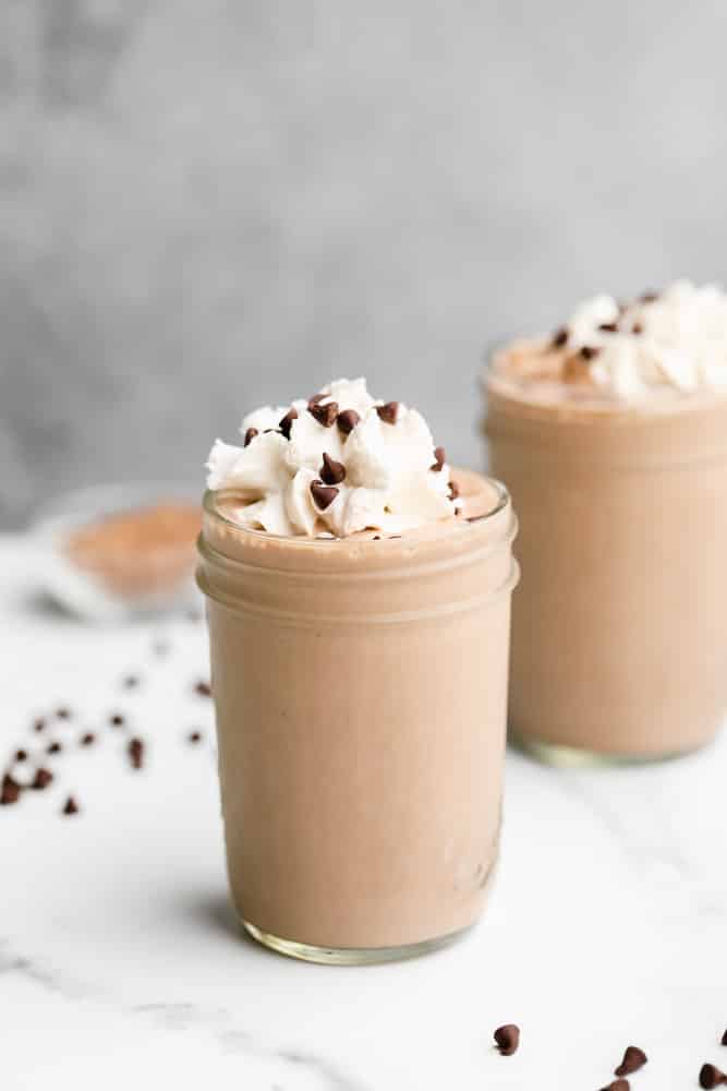 mason jar filled with a chocolate shake topped with whipped cream and chocolate chips