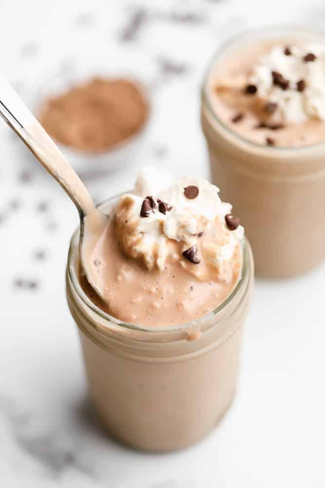 spoon taking a scoop of a chocolate shake out of a mason jar