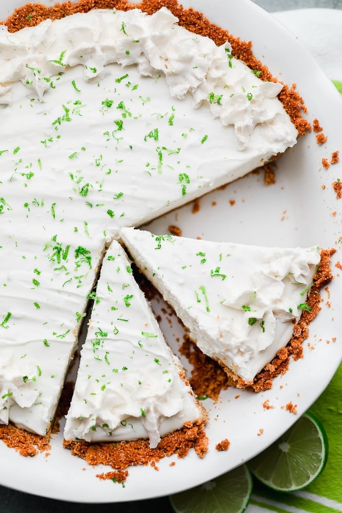 cut slices of key lime pie in a white pie plate