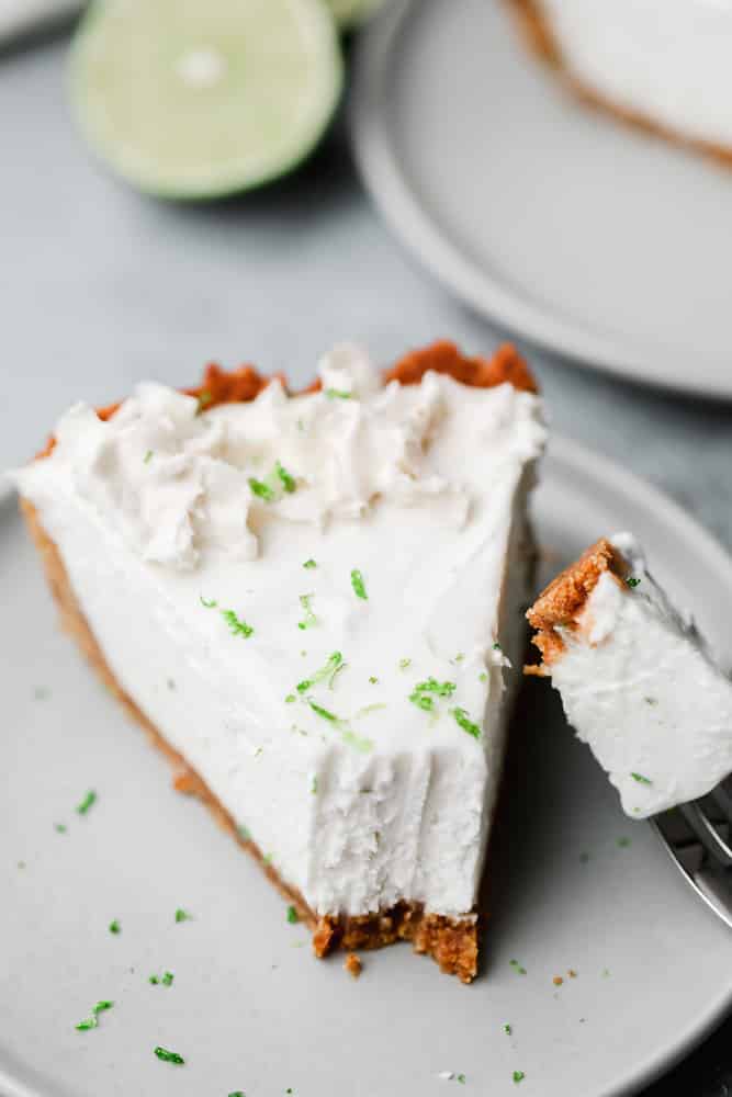 close up on a slice of white key lime pie with a fork taking a bite