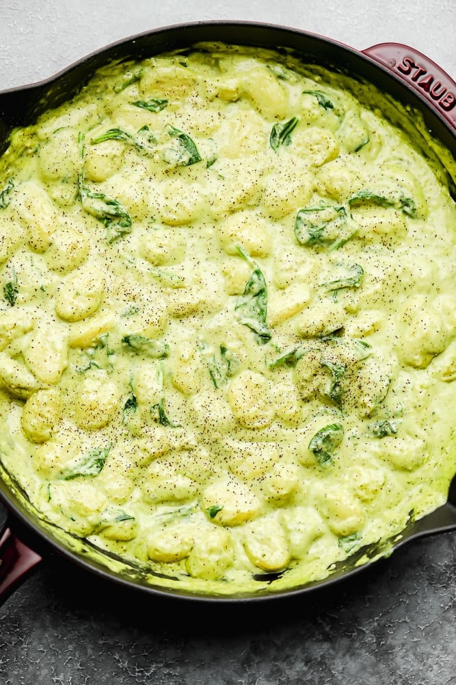 large pot filled with a green cream sauce and gnocchi