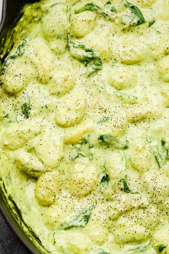 close up on creamy green gnocchi in a pot