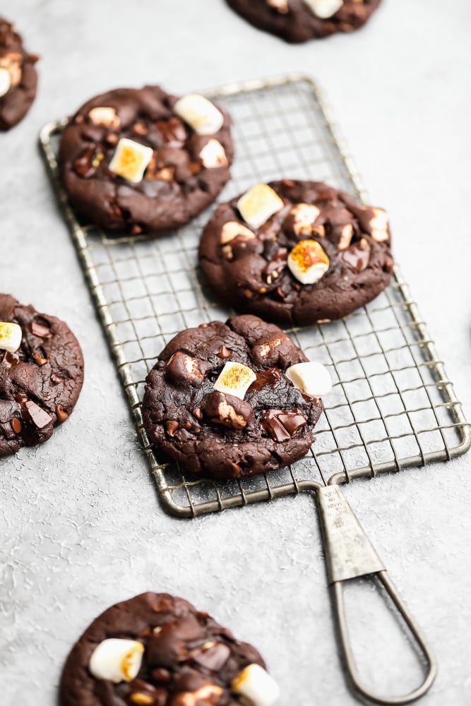 3 baked chocolate marshmallow cookies on a wire cooling rack