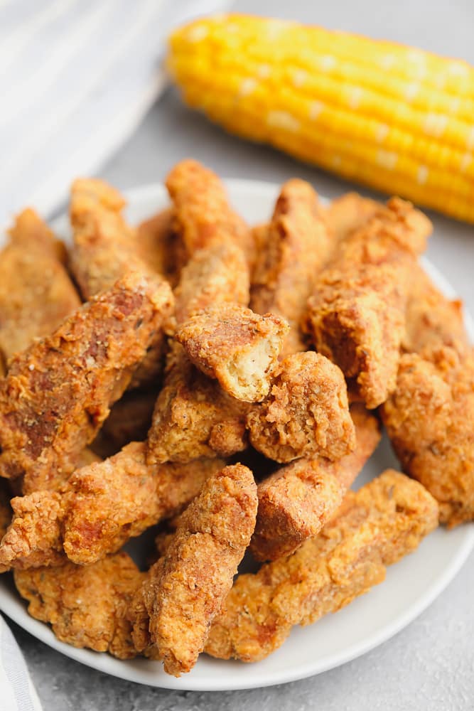large plate filled with golden brown fried vegan chicken pieces