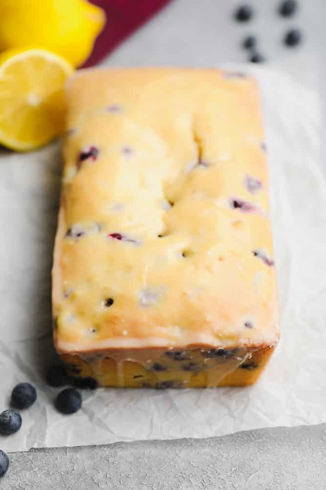 glazed loaf of blueberry and lemon bread on a piece of parchment paper