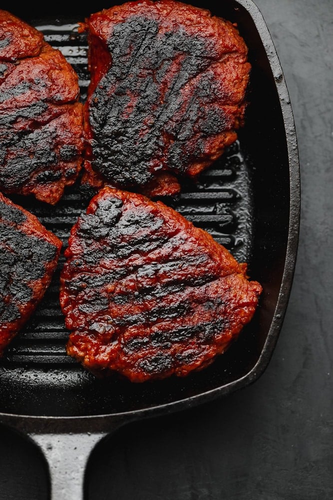 4 charred vegan steak patties in a black grill pan