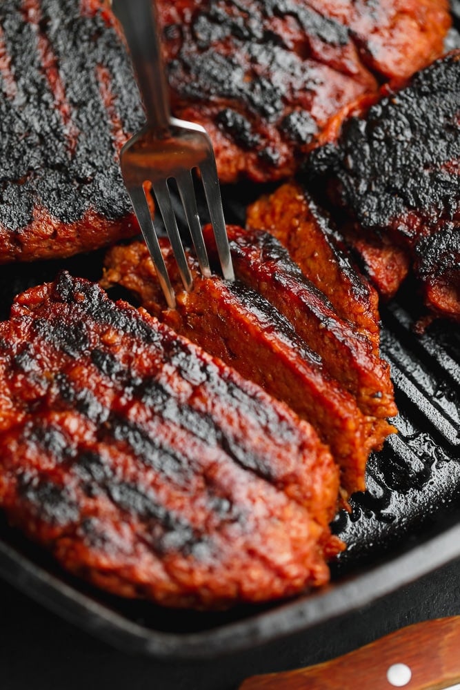 fork taking a slice of vegan steak out of a grill pan