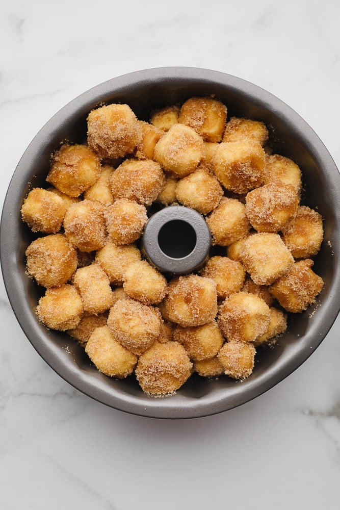 balls of cinnamon sugar coated dough in a bundt pan
