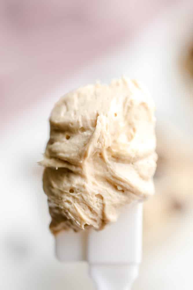 close up on a white spatula holding a scoop of beige peanut butter mousse