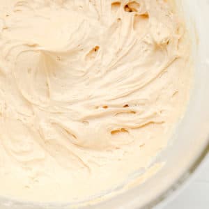 close up on a glass bowl filled with a beige, creamy peanut butter mousse
