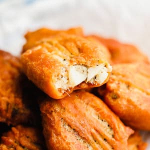 piece of vegan fried fish with a bite missing on top of a pile of more vegan fish