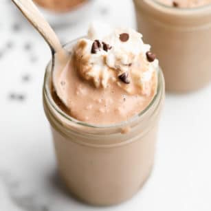 spoon taking a scoop of a chocolate shake out of a mason jar