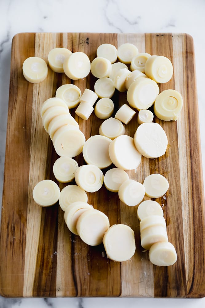 white round pieces of sliced hearts of palm on a wood cutting board