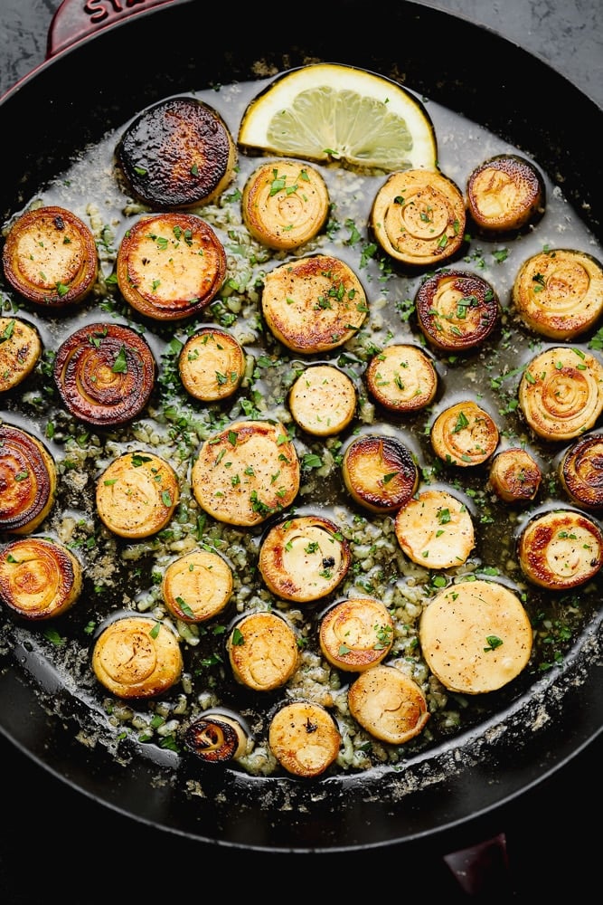 cooking golden brown vegan scallops in a large black skillet