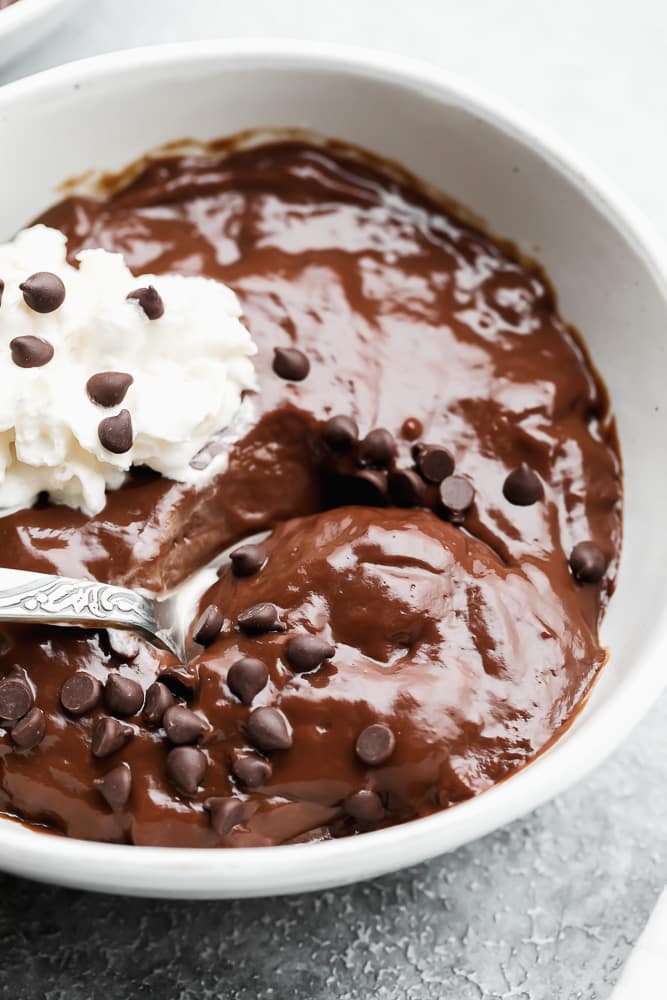 close up on a spoon taking a scoop of chocolate pudding out of a white bowl
