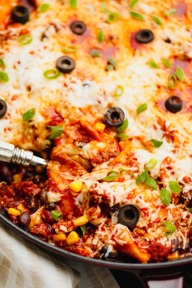 close up of skillet enchiladas with a spoon in it