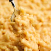close up of a spoon taking a scoop of mac and cheese from a skillet