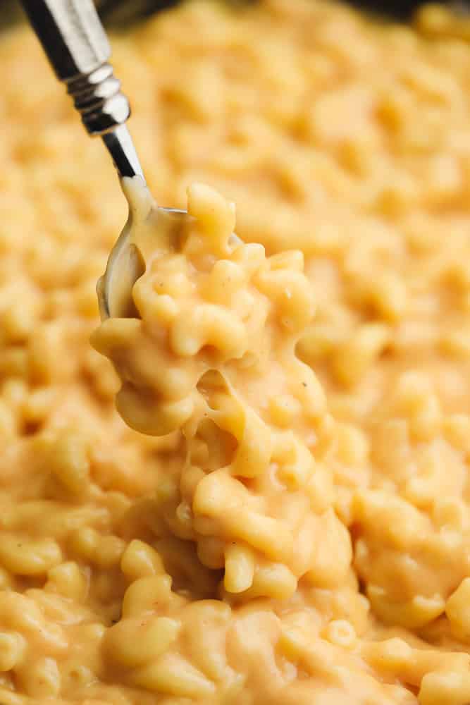 close up of a spoon taking a scoop of mac and cheese from a skillet