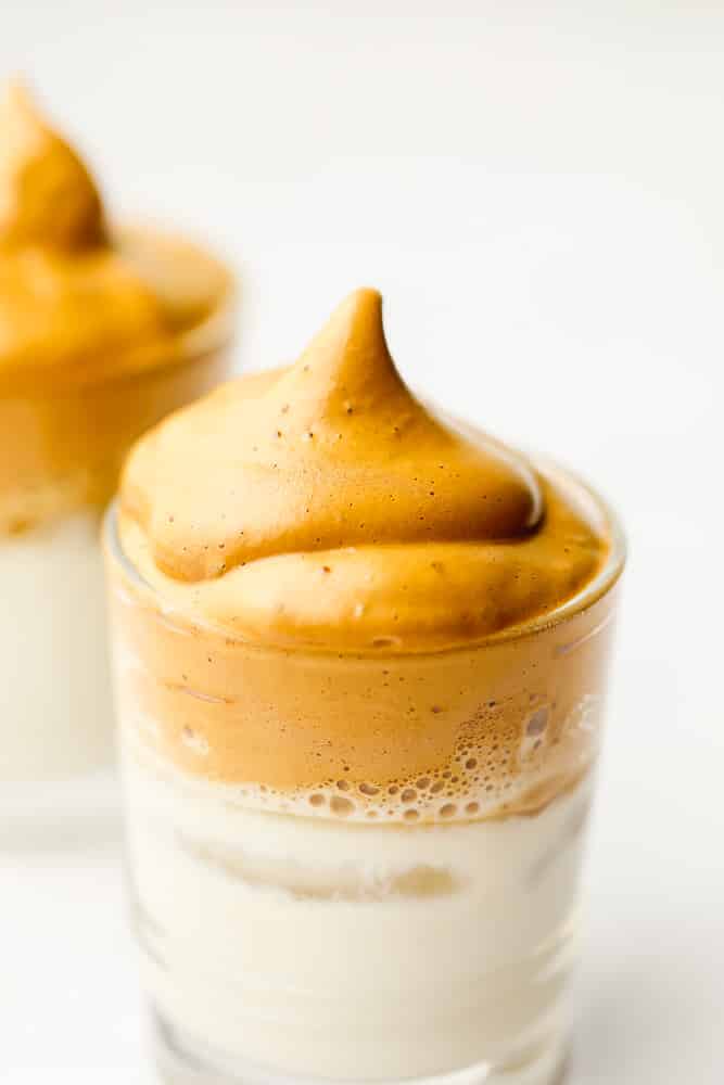 close up on a glass with milk topped with whipped coffee