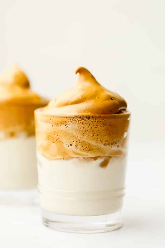 close up on a glass with milk topped with whipped coffee