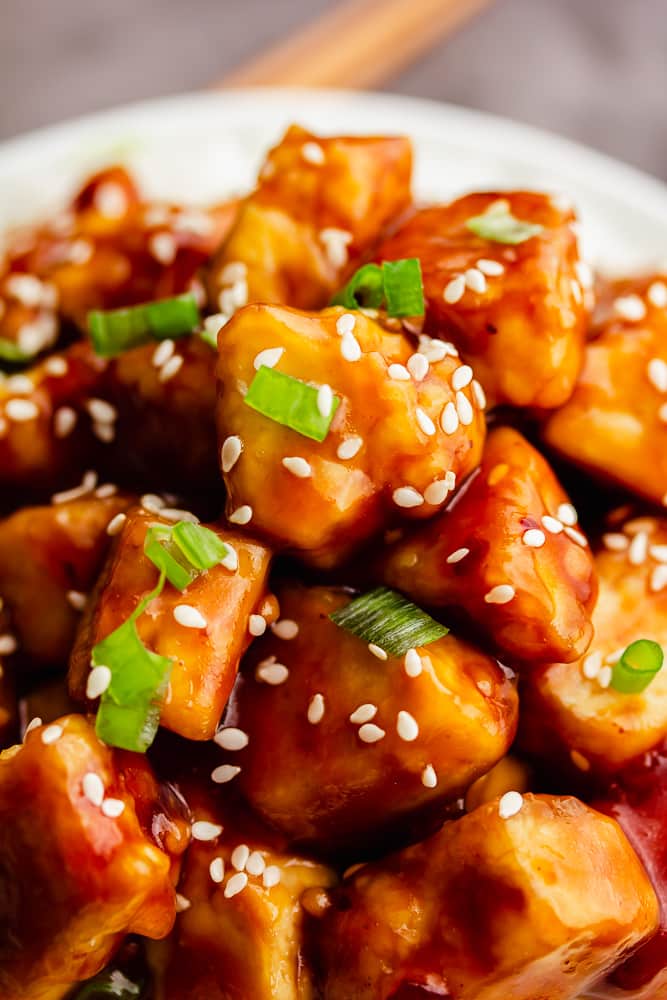 close up of general tsos tofu with chopped green onions and sesame seeds