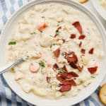 square image of a bowl of soup with pieces of red bacon on top