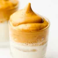 close up on a glass with milk topped with whipped coffee